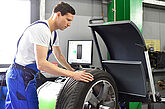 Autoreifen wird in einer Kfz-Werkstatt auf einer Auswuchtmaschine ausgewuchtet.