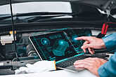 Mechaniker steht mit einem Tablet vor einem Auto