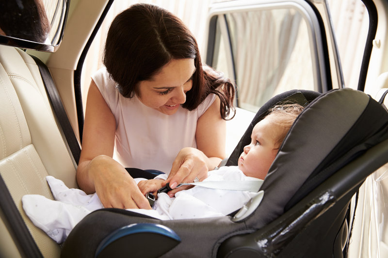 Mutter beugt sich über Kleinkind in Babyschale