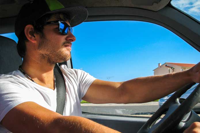 Autofahrer mit Kappe und Sonnenbrille in überhitztem Auto