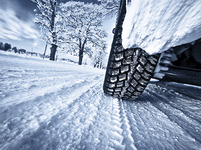 Auto fährt mit Winterreifen über verschneite Fahrbahn