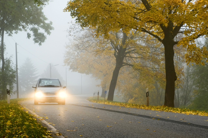 Fahrzeug auf Landstraße mit leuchtenden Scheinwerfern